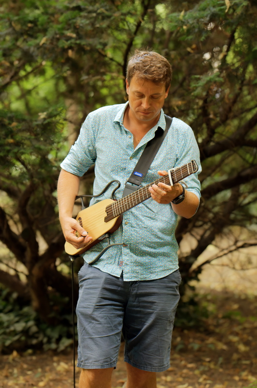 Person playing a Donner HUSH-I silent travel guitar, featuring a headless design with a compact wooden body